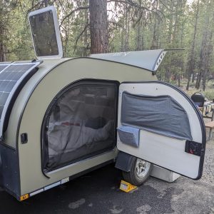A bug screen is closed on Droplet trailer, protecting the cabin from potential pesks in a campground.